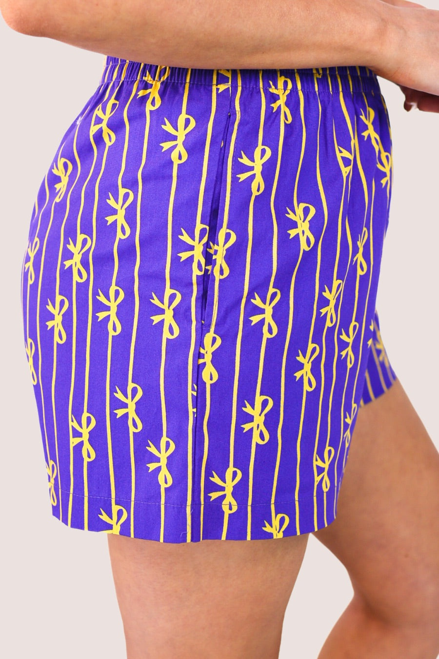 mid-rise relaxed fit boxer shorts with side pockets and an elastic waistband, designed on a bow and stripe pattern print and a solid base in purple
