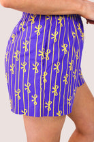 mid-rise relaxed fit boxer shorts with side pockets and an elastic waistband, designed on a bow and stripe pattern print and a solid base in purple
