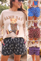 mid-rise relaxed fit boxer shorts with side pockets and an elastic waistband, designed on a bow and stripe pattern print and a solid base in black, blue, maroon, and purple