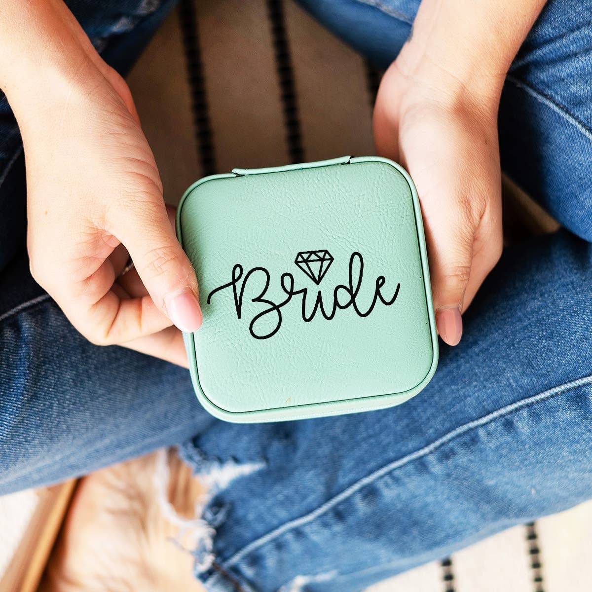 Green compact mirror with 'Bride' text held by a person wearing blue jeans.