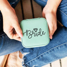 Green compact mirror with 'Bride' text held by a person wearing blue jeans.