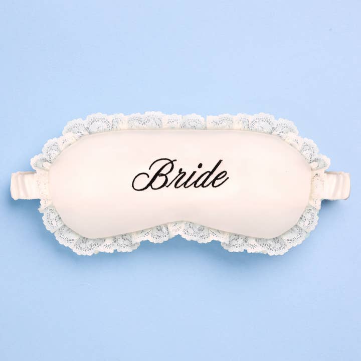 Sleep mask with lace trim and 'Bride' text on a light blue background
