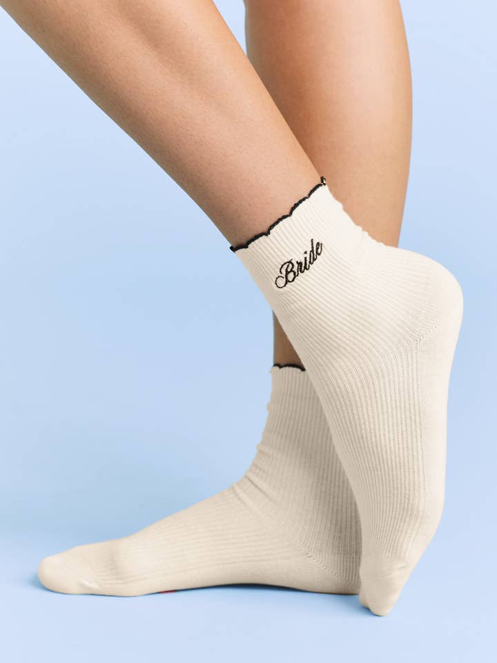 Beige socks with 'Bride' text on a light blue background