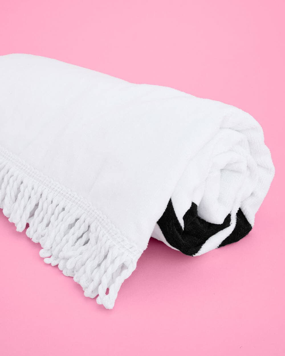 White towel with black trim on a pink background