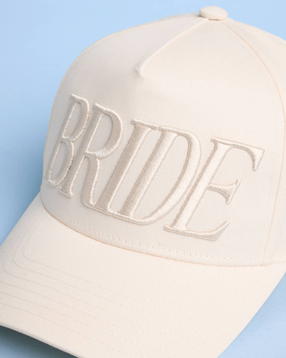 Beige cap with 'BRIDE' text on a light blue background