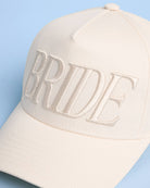 Beige cap with 'BRIDE' text on a light blue background
