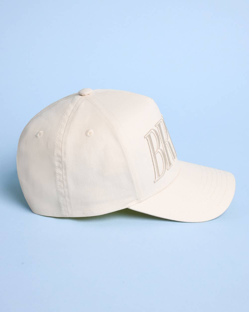 Beige cap with 'BILLY' embroidery on a light blue background