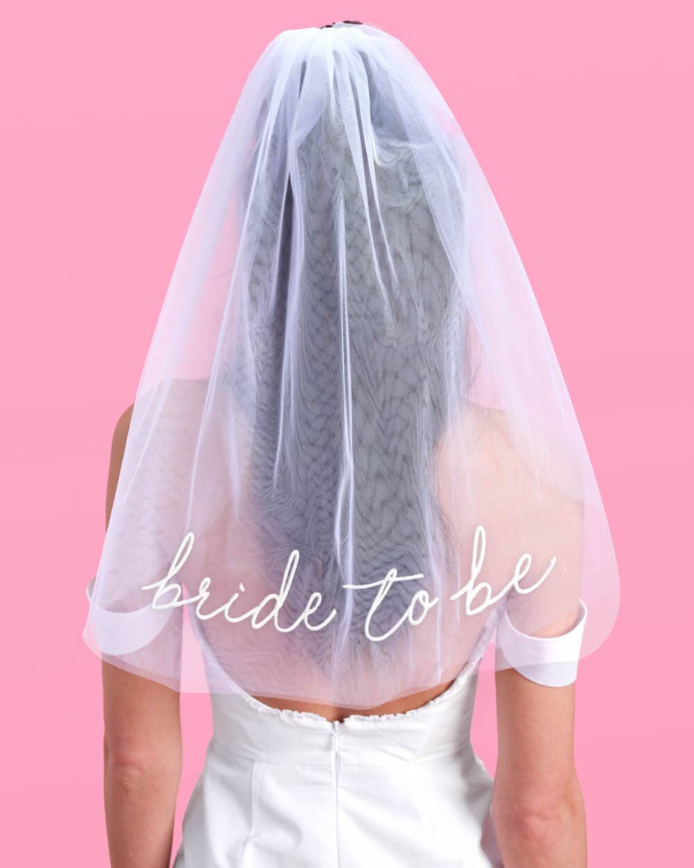 Person wearing a white veil with 'bride to be' text on a pink background