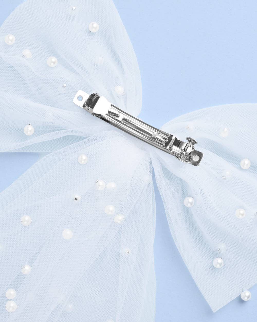 Hair bow with pearl embellishments and a hair clip on a light blue background
