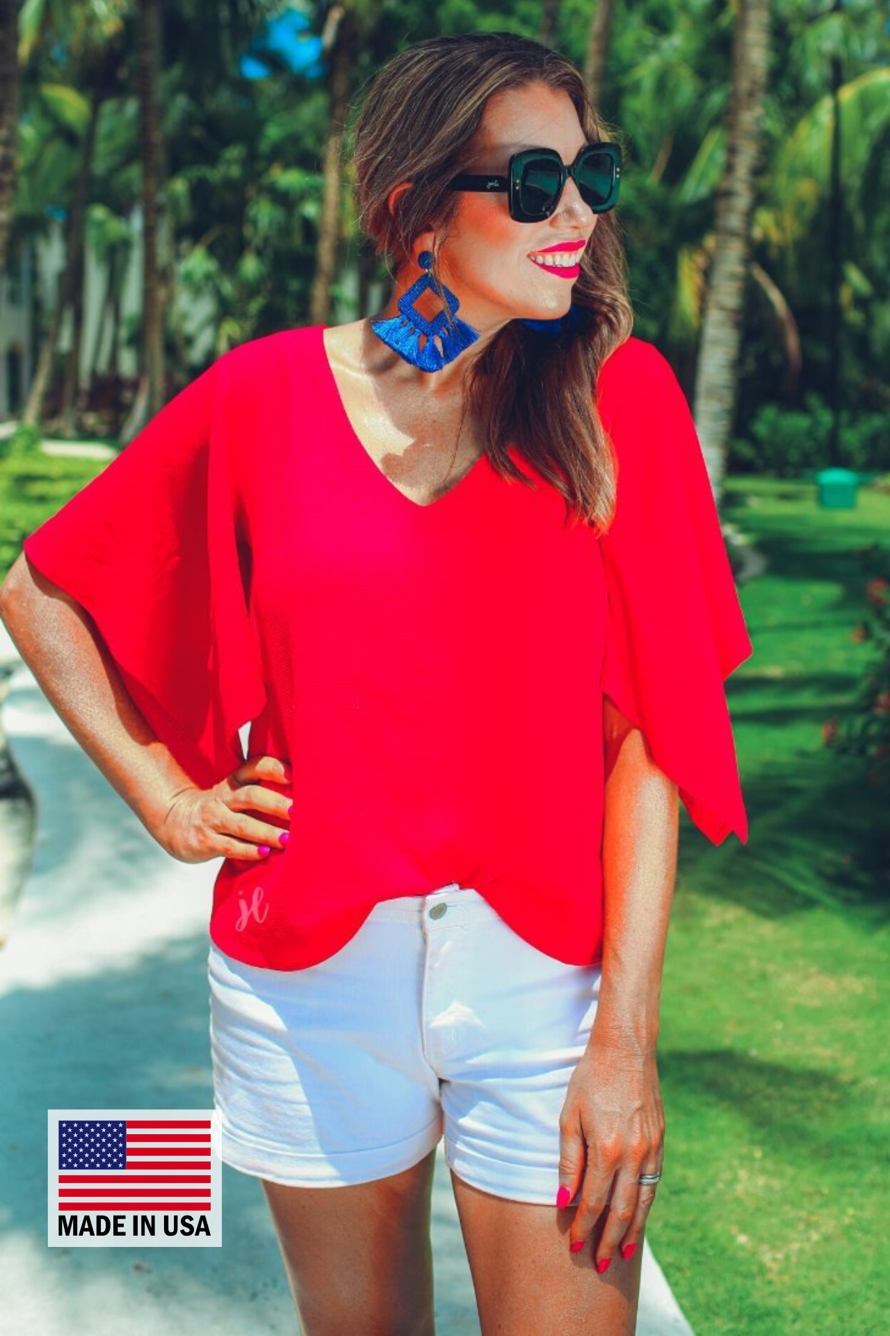 a red v-neck blouses crafted from lightweight textured fabric with asymmetrical half-flutter sleeves, front lining, and a relaxed fit, accented by a MADE IN USA watermark in the bottom left-hand corner