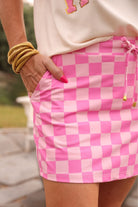 mid-rise relaxed fit everyday skort made of lightweight material with built-in cream shorts, drawstring tie with gold bead accents, an elastic band on the back, and side pockets, designed on a two-tone pink checkered pattern print fabric