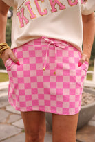 mid-rise relaxed fit everyday skort made of lightweight material with built-in cream shorts, drawstring tie with gold bead accents, an elastic band on the back, and side pockets, designed on a two-tone pink checkered pattern print fabric