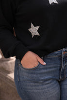 a black long-sleeve cropped sweatshirt with a crew neckline, drop-shoulder fit, rhinestone star detailing, and ribbed trim at the cuffs, hemline, and neckline