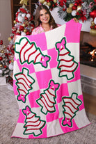 ultra-soft throw on a bold pink and white checkered background decorated with whimsical Christmas tree treats, each topped with an adorable pink bow