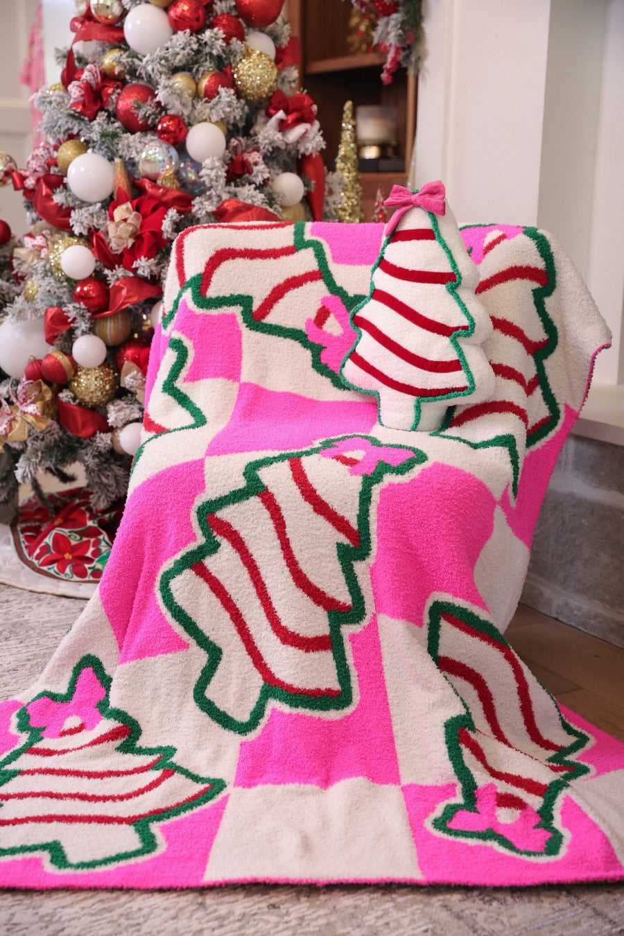 ultra-soft throw on a bold pink and white checkered background decorated with whimsical Christmas tree treats, each topped with an adorable pink bow paired with our Bow Christmas Treat Pillow