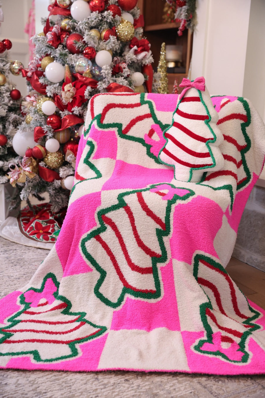 ultra-soft throw on a bold pink and white checkered background decorated with whimsical Christmas tree treats, each topped with an adorable pink bow paired with our Bow Christmas Treat Pillow