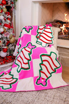 ultra-soft throw on a bold pink and white checkered background decorated with whimsical Christmas tree treats, each topped with an adorable pink bow paired with our Bow Christmas Treat Pillow
