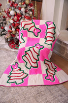 ultra-soft throw on a bold pink and white checkered background decorated with whimsical Christmas tree treats, each topped with an adorable pink bow