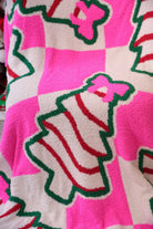 ultra-soft throw on a bold pink and white checkered background decorated with whimsical Christmas tree treats, each topped with an adorable pink bow