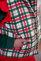 lightweight quilted puffer vest with a festive ivory, green, and red plaid pattern, snap-front closure, flattering fit, practical pockets, and whimsical red ruffle shoulder detail