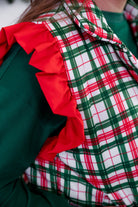 lightweight quilted puffer vest with a festive ivory, green, and red plaid pattern, snap-front closure, flattering fit, practical pockets, and whimsical red ruffle shoulder detail