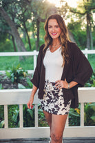 mid-rise relaxed fit everyday skort made of lightweight material with built-in cream shorts, drawstring tie with gold bead accents, an elastic band on the back, and side pockets, designed on a brown cow pattern print fabric and cream base