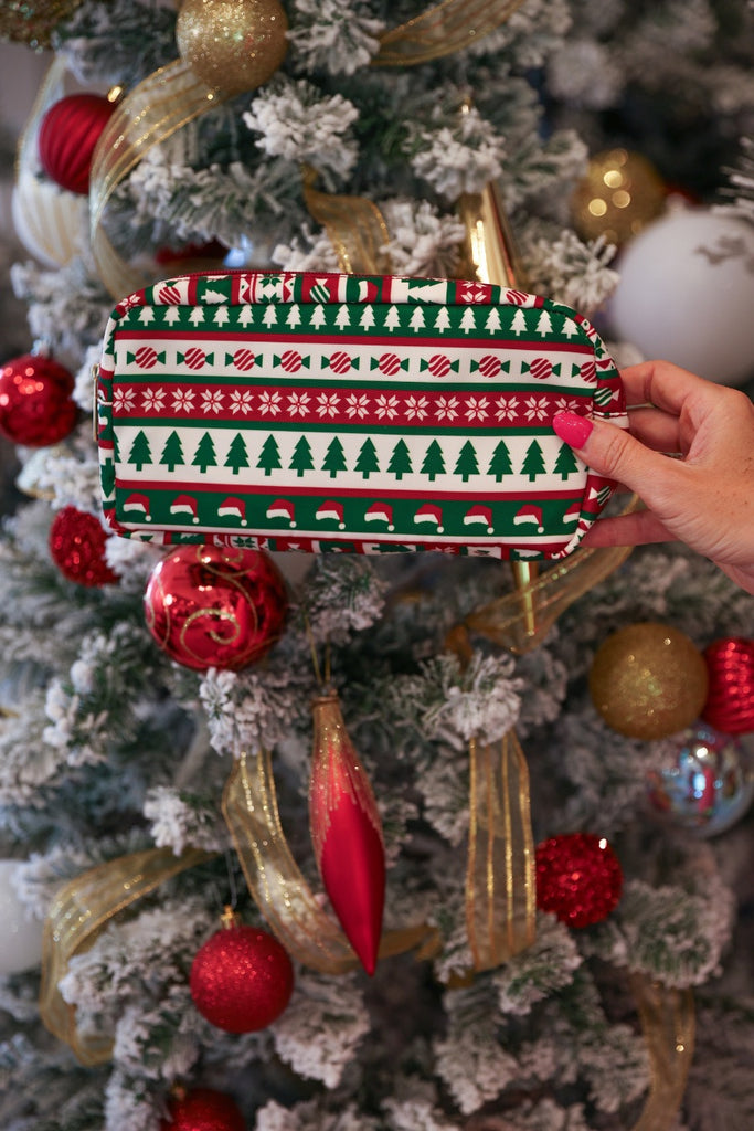 a zipper-closure travel bag with a festive holiday pattern of Christmas trees, Santa hats, wrapped candy, and snowflakes