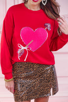 a long-sleeve pullover made from luxe material with a classic crew neckline, a relaxed drop-shoulder fit, and a statement chenille heart accented with intricate embroidery and a sequins bow-and-arrow detail