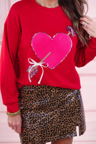a long-sleeve pullover made from luxe material with a classic crew neckline, a relaxed drop-shoulder fit, and a statement chenille heart accented with intricate embroidery and a sequins bow-and-arrow detail