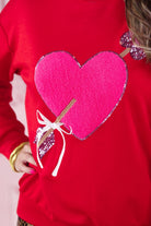 a long-sleeve pullover made from luxe material with a classic crew neckline, a relaxed drop-shoulder fit, and a statement chenille heart accented with intricate embroidery and a sequins bow-and-arrow detail