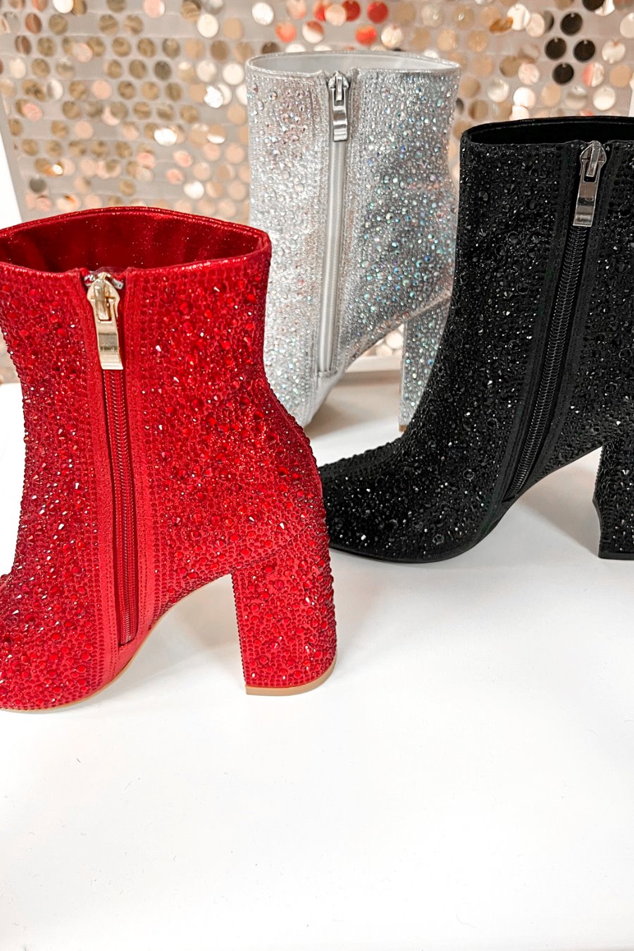 rhinestone-covered booties with a pointed toe, front seam, inside zipper, cushioned flatbed, and a 4" block heel in black, red, and silver
