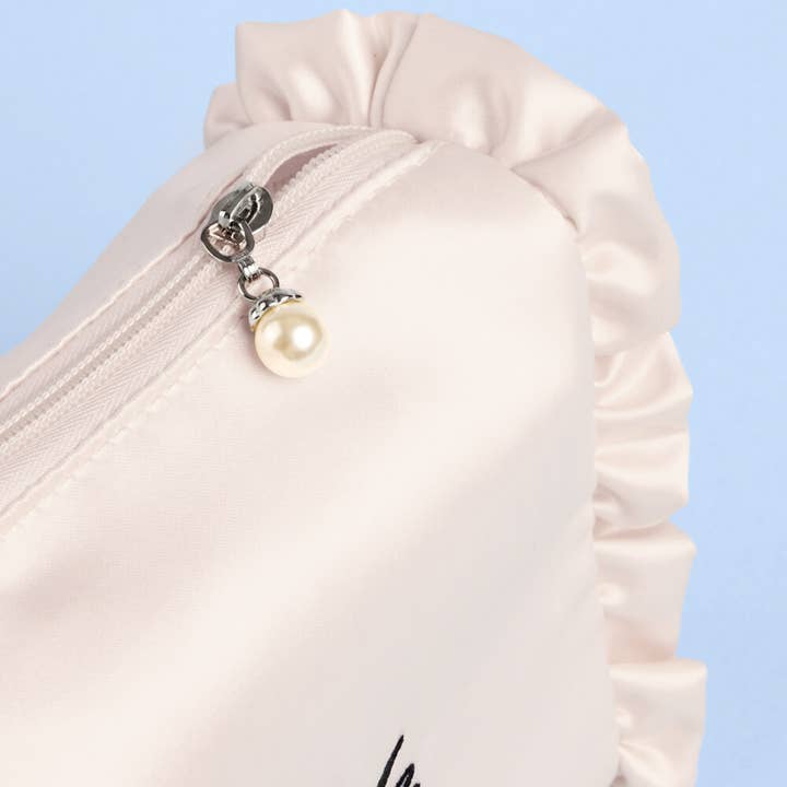 Close-up of a white garment with a pearl zipper pull on a light blue background