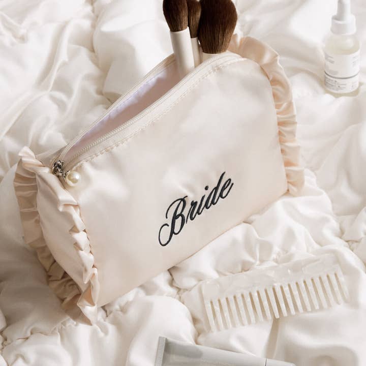 Makeup bag labeled 'Bride' on a soft white surface with makeup items.