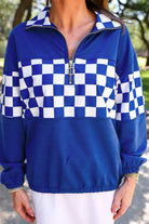 a relaxed blue half-zip pullover with gold zipper detail, checkerboard contrast panels, long sleeves, elasticized cuffs, and a softly gathered bottom hem