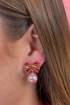 lightweight pink enamel bow stud trimmed in gold with a dangling iridescent pearl finished with a comfort disc backing