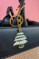 a festive layered green enamel fir Christmas tree with snowy white detailing, sprinkled with red and crystal accents, and crowned with a shimmering gold star, complete with a gold-tone swivel clasp and matching keyring