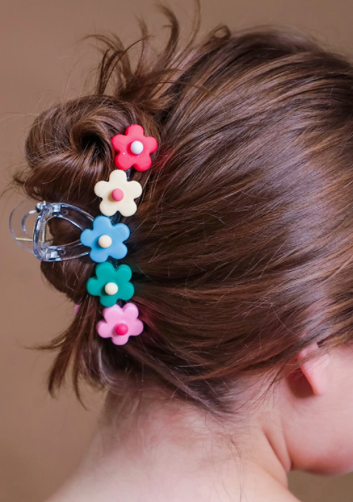 Multicolor flower-shaped hair clip in a bun against a neutral background