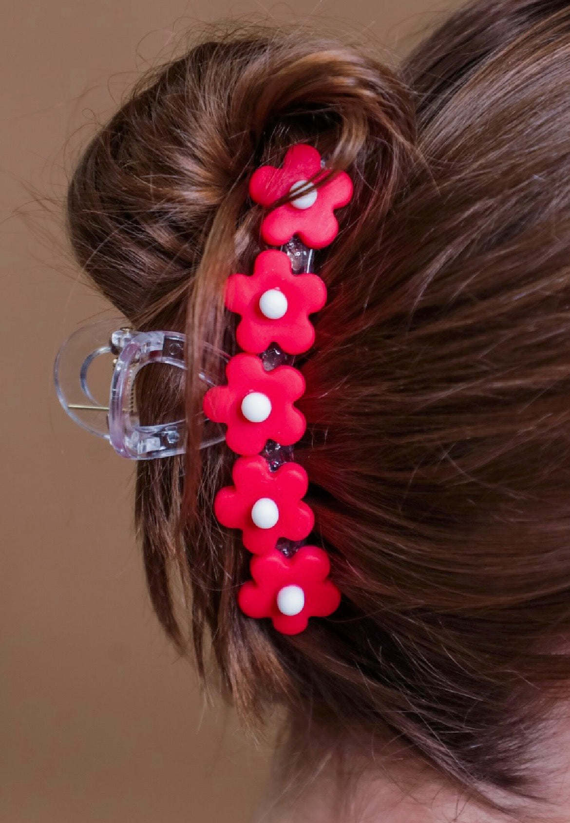 Red flower-shaped hair clip in a bun against a neutral background