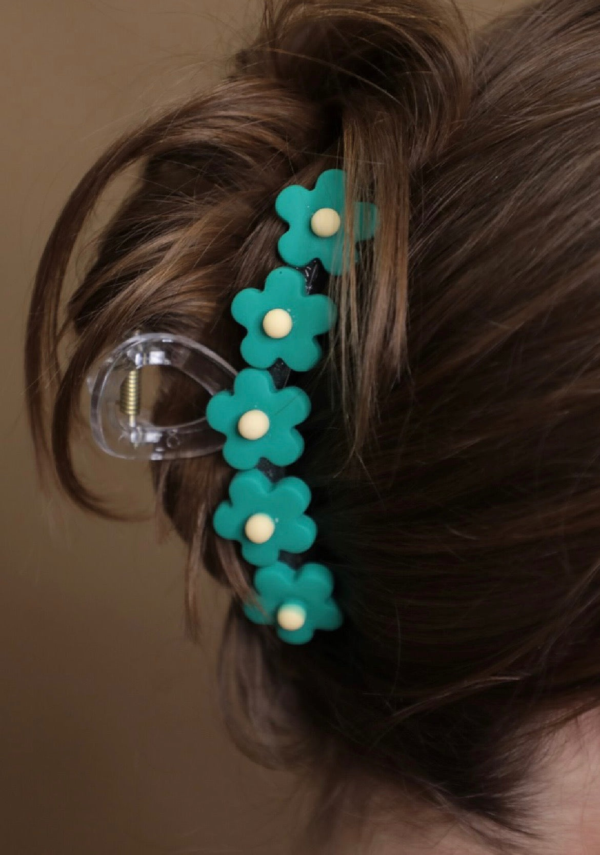 Teal flower-shaped hair clip in a bun against a neutral background