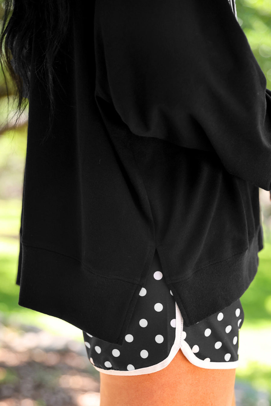 a relaxed black French terry pullover with a V-neckline, mixed polka dot and gingham 'GAME DAY' lettering, long sleeves, banded cuffs, and side slit hems on a cotton fabric