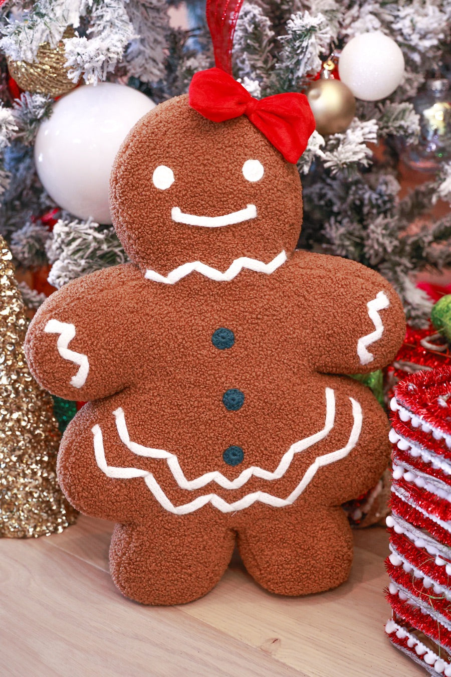 brown gingerbread girl fluffy pillow with dainty white icing details, stitched forest green buttons, and an adorable red bow