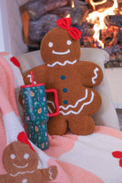 brown gingerbread girl fluffy pillow with dainty white icing details, stitched forest green buttons, and an adorable red bow with coordinating blanket and tumbler