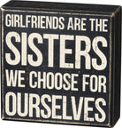 Black box sign with white text about girlfriends and sisters.