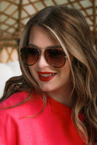 brown aviator sunglasses with thin round wireframes, tinted lenses, UV protection, and brand name detail (on both the temple and the complimentary black pouch)