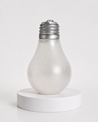 a glow-in-the-dark light bulb squishy with a frosted translucent body, metallic silver cap, soft squeezable texture, and classic bulb-inspired shape
