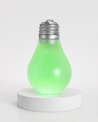 a glow-in-the-dark light bulb squishy with a frosted translucent body, metallic silver cap, soft squeezable texture, and classic bulb-inspired shape