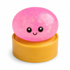 a pink mystery dumpling-shaped squishy fidget with assorted surprise colors, glittery finish, kawaii face, soft squeezable texture, and glow-in-the-dark feature
