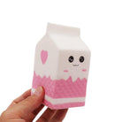 a white milk-carton squishy with a kawaii face, pink-and-white colorblock design, textured accent panel, side heart detail, squeezable sensory feel, and clear individual packaging
