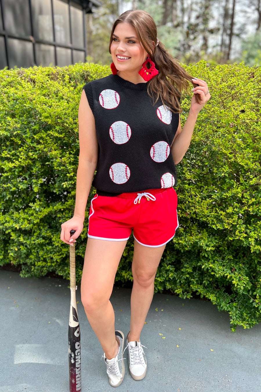 a black sleeveless sweater vest with an oversized fit, an allover textured baseball motif, and ribbed trim at the neckline, arm openings, and hem