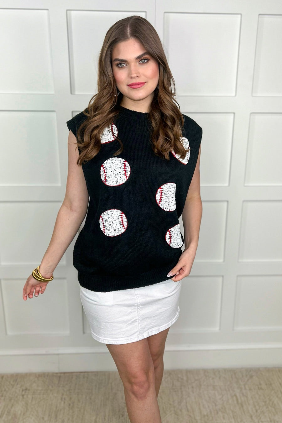 a black sleeveless sweater vest with an oversized fit, an allover textured baseball motif, and ribbed trim at the neckline, arm openings, and hem